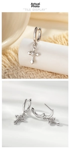 Macro detail of silver cross pendant earrings with zircon stone on woven background