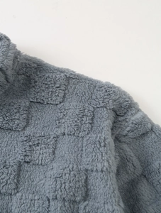 Détail macro du sweat à capuche gris montrant la texture douce à carreaux en polaire