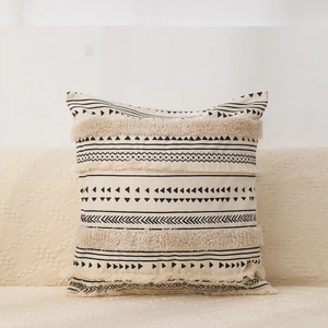 Detail of bohemian cream cotton pillow cover with black geometric tufting and tassels
