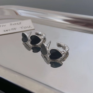 Detail of silver heart hoop earrings with black enamel finish on metal tray