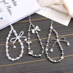 Detailed view of beaded phone charms featuring imitation pearls and elegant bow accents