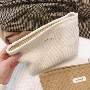 Close-up of minimalist woven knitted cosmetic bag with simple wish textile label