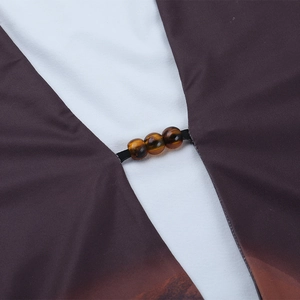 Macro detail of sexy V-neck dress with tiger eye stone beads and gradient printed fabric