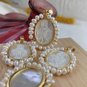 Gros plan détaillé de pendentifs Vierge Marie en nacre avec bordure en perles d'eau douce.