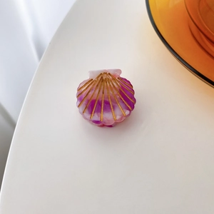 Macro shot of shell-shaped hair clip with purple and white marble texture and gold lines