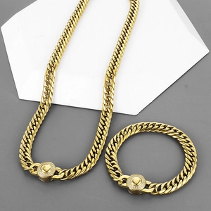 Macro view of gold Cuban chain set with diamond-encrusted round clasp on white pedestal
