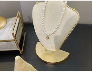Elegant pearl necklace with green gemstone pendant on white velvet jewelry display stand