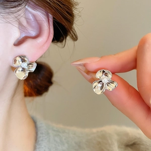Detail of silver flower earrings with hammered petals and pearl center on ear