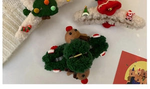 Flat lay of Christmas plush hair claws featuring Reindeer, Santa and Xmas tree motifs