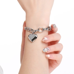 Close-up of heart charm on polished silver chain bracelet worn on a female wrist