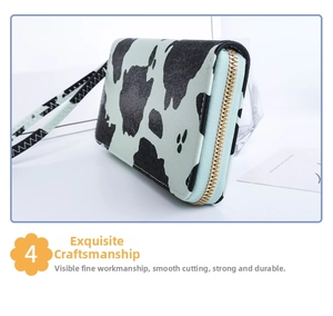 Detail of a cow print long wallet with gold zipper and a matching leather wrist strap