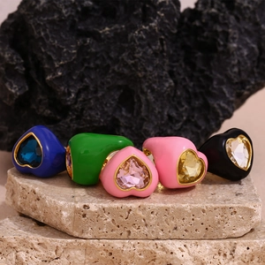 Macro detail of five colorful enamel heart rings set on natural stone displays