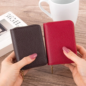 Detailed view of red and brown litchi grain leather card holders with gold zippers