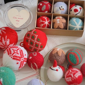 Macro detail of red knitted wool Christmas tree ornaments with festive felt patterns