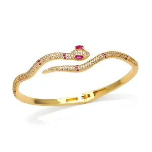 Elegant gold snake bracelet with white cubic zirconia and red gem eyes on white background