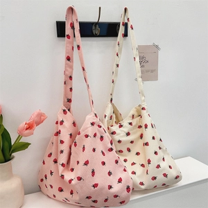 Détail de sacs fourre-tout en velours côtelé rose et beige avec motif fraises sur crochets