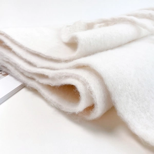 Close-up of thick white mohair scarf texture showing soft fuzzy felt material detail