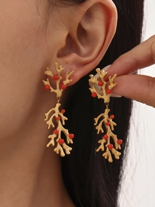 Detail of coral-shaped 18k gold plated earrings with matte texture and red beads
