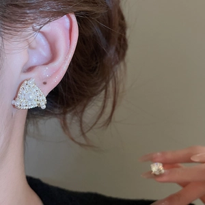 Close-up of elegant triangle pearl stud earring with sparkling zircons on model ear