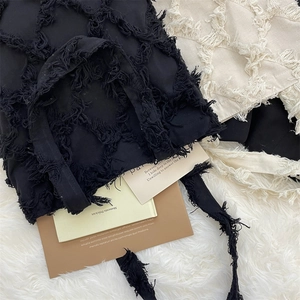 Close-up of fringe canvas tote bags in black and beige with diamond texture details