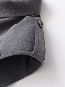 Gros plan détaillé sur le tissu gris avec bouton marron foncé et coutures précises