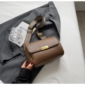 Détail du sac en cuir marron à motif litchi avec bandoulière large en jacquard tissé