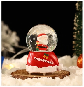 Gros plan d'une boule à neige Père Noël avec base chapeau rouge sur disque de bois