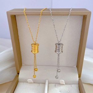 Detailed close-up of gold and silver cylinder pendant necklaces with delicate tassel drops