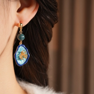 Detail view of vintage blue enamel earrings with stones on model for retro style