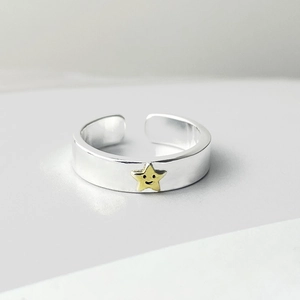 Detailed macro view of silver open ring featuring a golden smiling star centerpiece