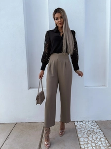 Close-up of black shirt featuring intricate lace sleeves and beige wide-leg trousers