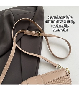 Close-up of woven texture and adjustable leather strap with gold buckle on apricot bag