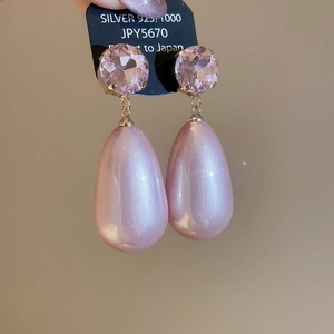 Detailed macro view of pink crystal and teardrop pearl earrings with gold 925 silver studs