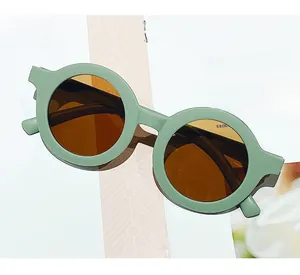 Detail view of round light green matte kids sunglasses on a lifestyle magazine background