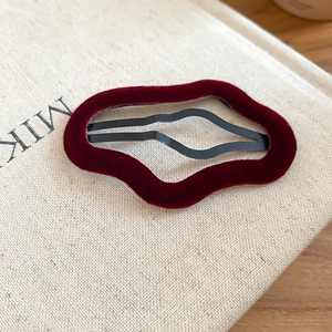 Close-up of a burgundy velvet geometric hair clip with irregular wave shape texture