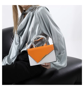 Detail of orange and white leather bag featuring a unique silver metallic handle and flap