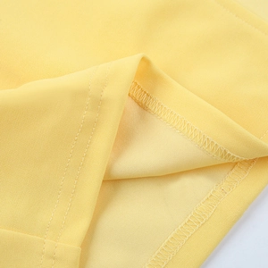 Gros plan détaillé du tissu jaune de la robe tricotée montrant les coutures de précision