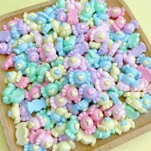 Macro shot of colorful resin candy nail charms with heart patterns in a wooden tray