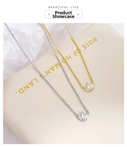 Detail of silver and gold clover necklaces with marquise crystals on a white backdrop