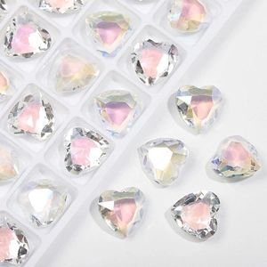 Close-up of faceted heart-shaped glass gems with iridescent shine on white background