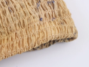 Macro shot of khaki smocked elastic fabric with detailed crinkle texture and stitching