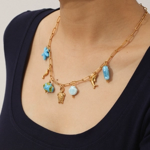 Détail de breloques étoile de mer, hippocampe et tortue sur un collier marin doré