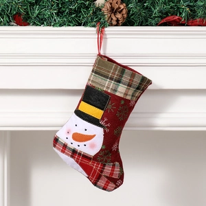Christmas stocking with snowman and red-green plaid hanging on a cozy fireplace