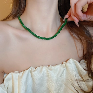 Gros plan d'un collier de perles géométriques vert émeraude porté par un modèle