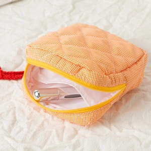 Close-up of quilted orange plaid cosmetic bag showing compact storage for lipstick