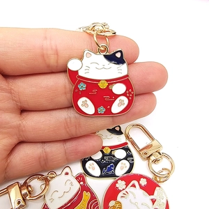 Japanese style Maneki Neko lucky cat alloy keychain pendant held in hand for scale