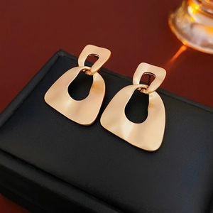 Matte gold geometric double-hoop earrings displayed on a premium textured surface