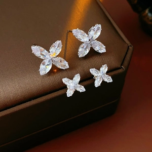 Vue macro de deux paires de boucles d'oreilles fleurs en zircon argenté sur un coffret