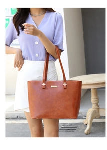 Brown faux leather tote bag with long handles shown in a lifestyle street photoshoot