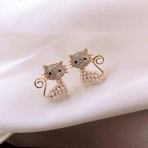 Detailed macro view of golden cat stud earrings with sparkling crystals and small pearls